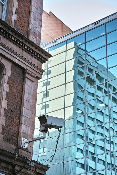 una telecamera appesa con staffa ad un palazzo di mattoni: è un elemento degli impianti speciali di videosorveglianza 